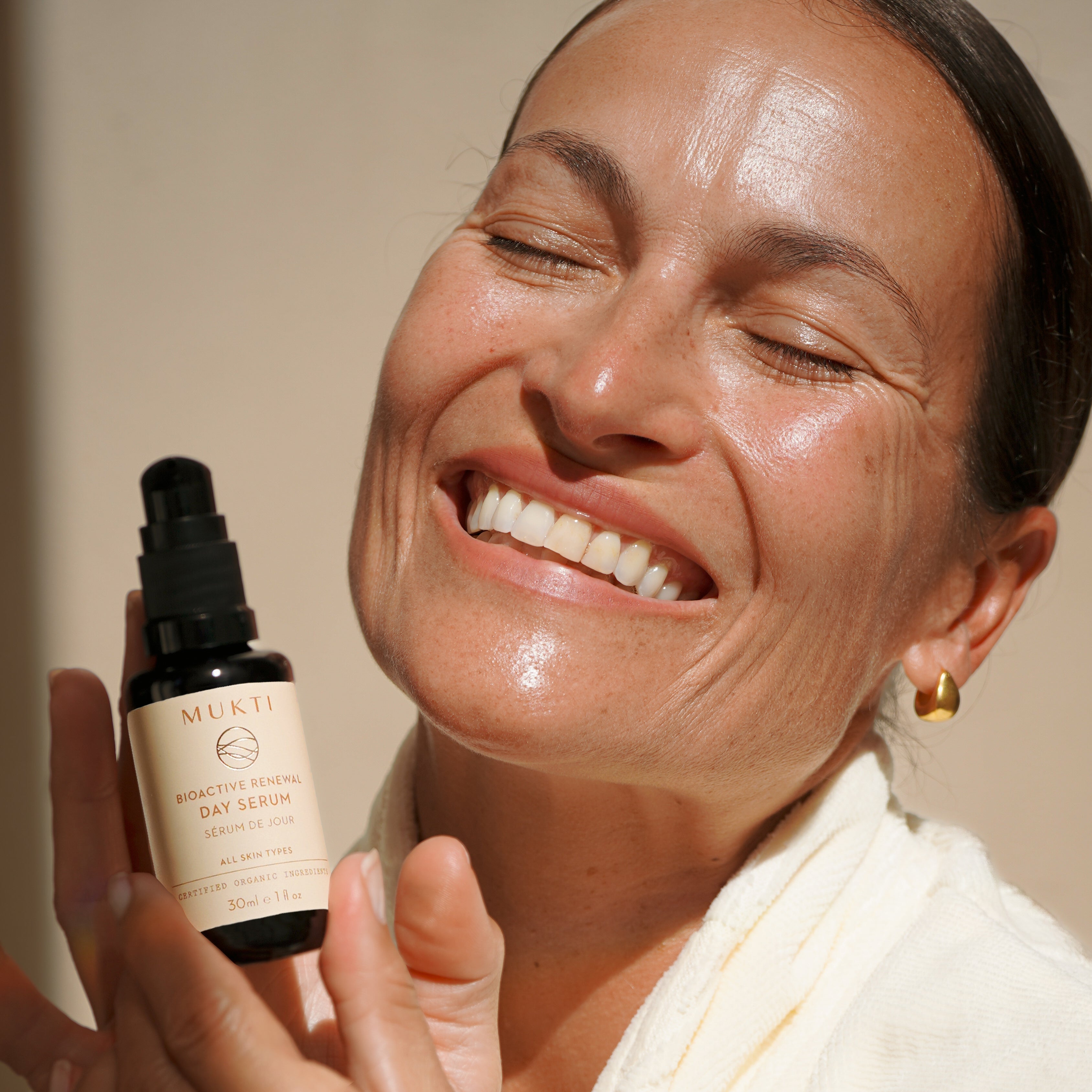 Smiling woman holding Mukti Bioactive Renewal Day Serum
