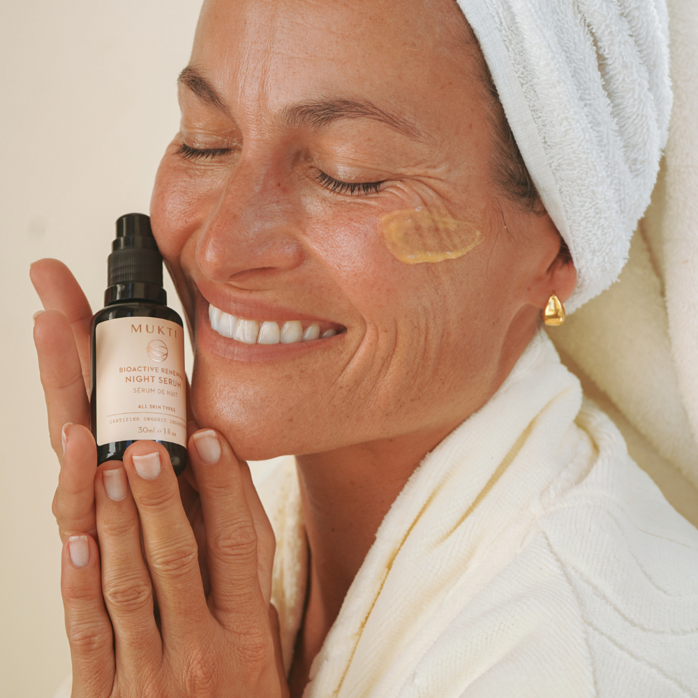 Smiling woman holding Mukti Bioactive Renewal Night Serum