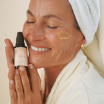 Smiling woman holding Mukti Bioactive Renewal Night Serum