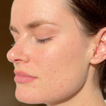 Close-up profile of a woman with calm hydrated skin after applying Mukti Barrier Repair Serum.