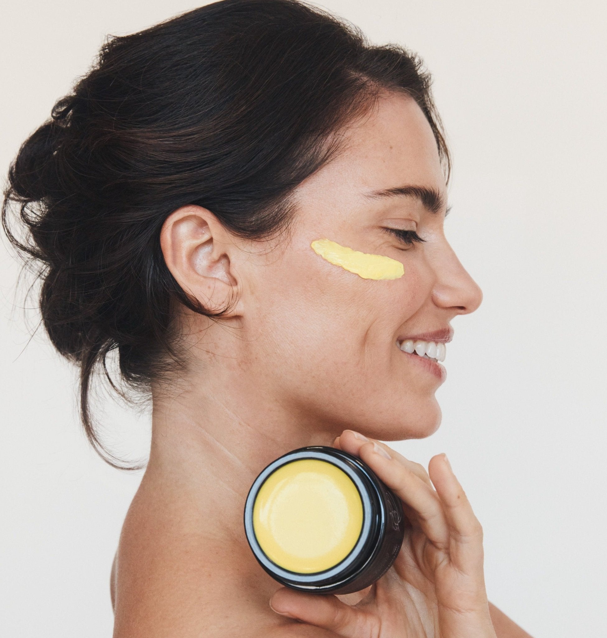 Woman holding Mukti Marigold Hydrating Creme to her neck