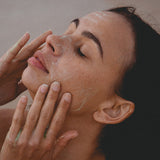 Woman relaxing with eyes closed while massaging Mukti 2-in-1 Resurfacing Exfoliant over her face.