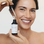 Smiling woman holding Mukti Vitamin B Elixir