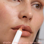 Close-up of a person holding a makeup pencil labeled 'shade - muse | pale terracotta'.