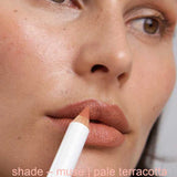 Close-up of a person holding a makeup pencil labeled 'shade - muse | pale terracotta'.