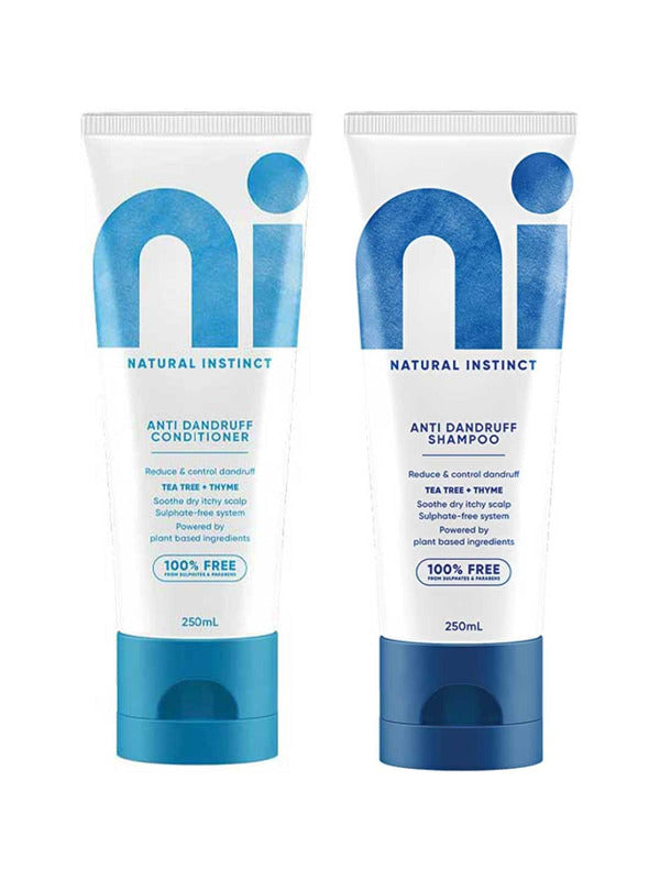 Two white Natural Instinct Anti-Dandruff tubes standing side by side: conditioner with turquoise lettering and cap, and shampoo with dark blue lettering and cap.