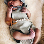 Newborn baby resting on a textured cream blanket while using an amber Natural Rubber Soother Small Rounded dummy.