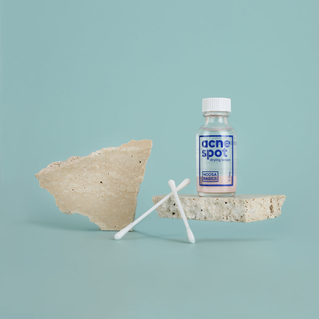 Noosa Basics Acne Spot Drying Lotion held while applying with a cotton bud