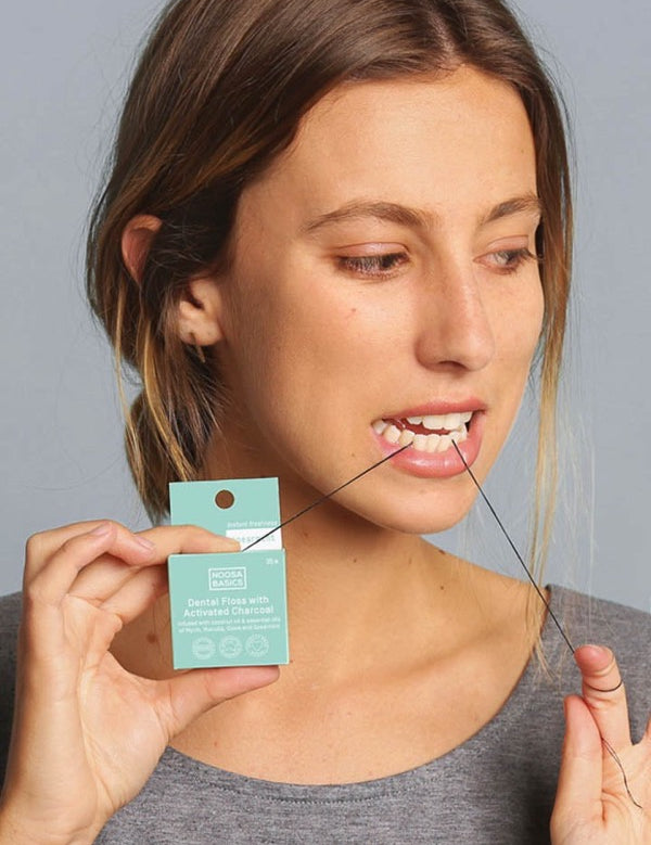 Woman using Noosa Basics bamboo charcoal dental floss
