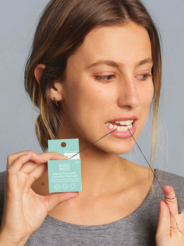 Woman using Noosa Basics bamboo charcoal dental floss
