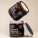 Open Noosa Basics Cocoa Butter and Shea Butter skin cream jars stacked with their silver lids on a warm beige surface.