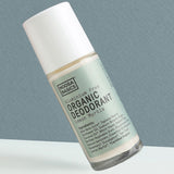 Clear Noosa Basics Lemon Myrtle roll-on deodorant bottle with a pale green label and white cap tilted diagonally against a grey-green background.