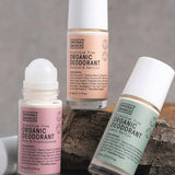 Three Noosa Basics roll-on deodorants arranged around a natural stone: Coconut and Vanilla, Lemon Myrtle, and Rose and Frankincense, with one roller ball exposed.