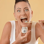 Woman holding Oh Gigi Flavour-Free Hydroxyapatite Tooth Powder and brushing her teeth