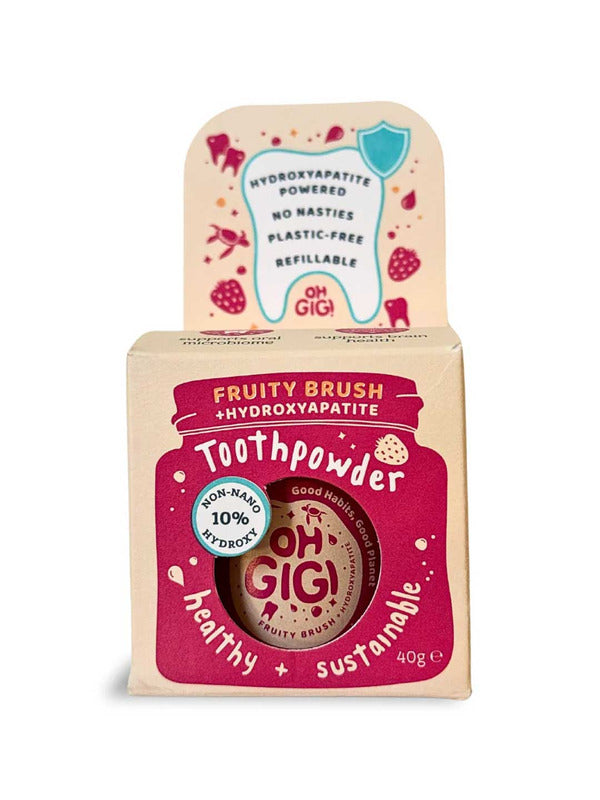 Kraft cardboard Oh Gigi Fruity Brush Toothpowder box with a raspberry-pink jar-shaped front panel and white lettering, topped by a tall tab decorated with a tooth outline and pink fruit illustrations.