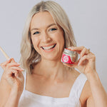 Woman smiling with a toothbrush and Oh Gigi Fruity Hydroxyapatite Tooth Powder