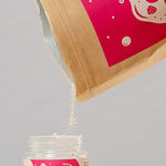 Oh Gigi Fruity Hydroxyapatite Tooth Powder refill being poured into its glass jar