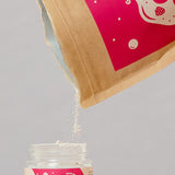 Oh Gigi Fruity Hydroxyapatite Tooth Powder refill being poured into its glass jar