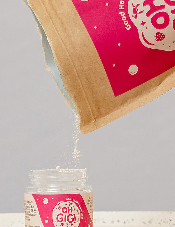 Oh Gigi Fruity Hydroxyapatite Tooth Powder refill being poured into its glass jar