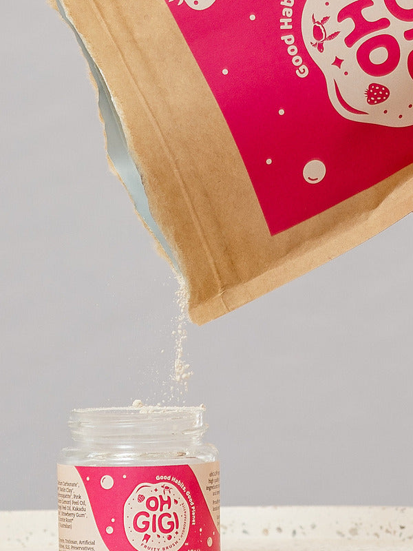 Oh Gigi Fruity Hydroxyapatite Tooth Powder refill being poured into its glass jar