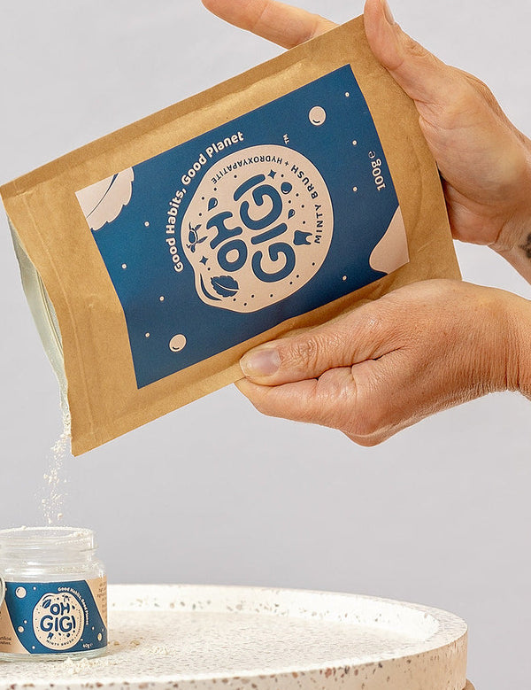 Oh Gigi Minty Hydroxyapatite Tooth Powder refill being poured into its glass jar