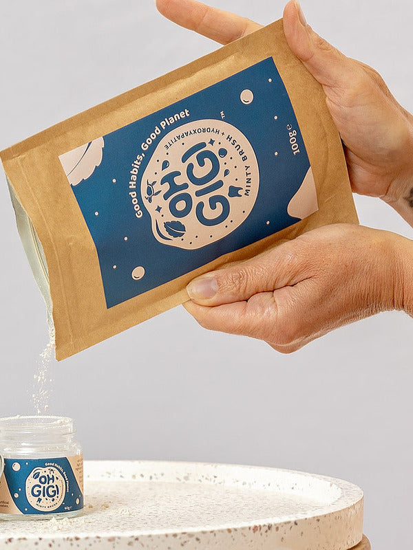 Oh Gigi Minty Hydroxyapatite Tooth Powder refill being poured into its glass jar