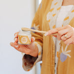 Person using Oh Gigi Native Hydroxyapatite Tooth Powder with a bamboo toothbrush