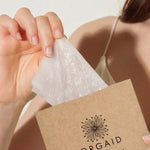 Woman removing an Orgaid Anti-Aging and Moisturising Organic Sheet Mask from its packet