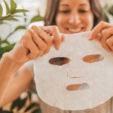 Woman smiling while preparing to apply an Orgaid Organic Sheet Mask