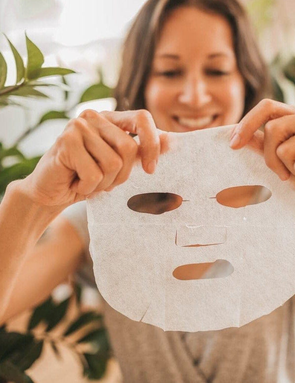 Woman smiling while preparing to apply an Orgaid Organic Sheet Mask
