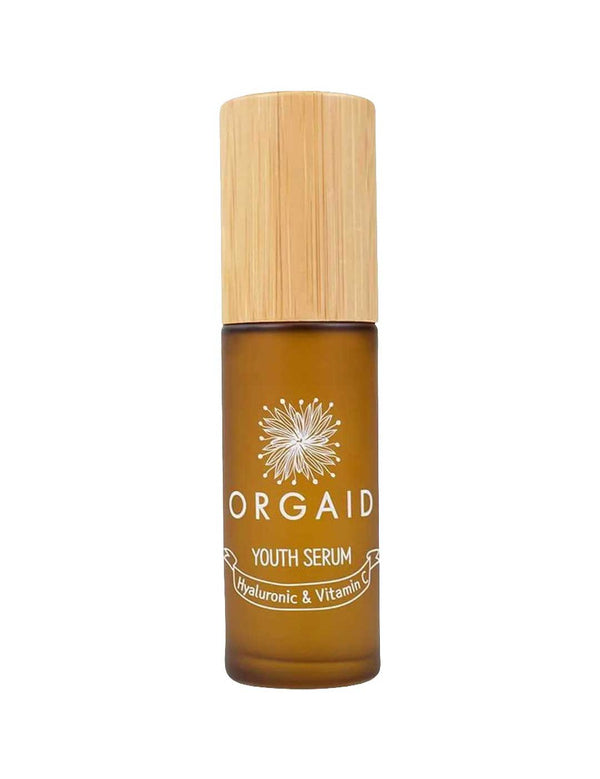 A 36ml brown glass bottle of Orgaid Youth Serum Hyaluronic and Vitamin C with a wooden cap, featuring a flower graphic label. This vitamin C serum blend helps brighten skin.
