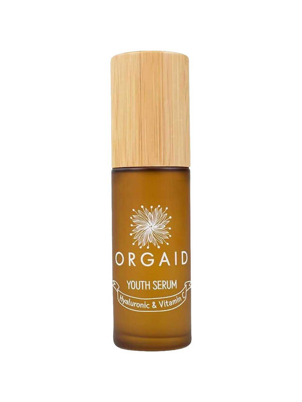 A 36ml brown glass bottle of Orgaid Youth Serum Hyaluronic and Vitamin C with a wooden cap, featuring a flower graphic label. This vitamin C serum blend helps brighten skin.