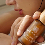 Woman holding Orgaid Youth Serum beside her face