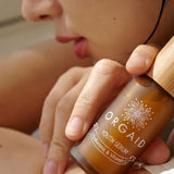 Woman holding Orgaid Youth Serum beside her face