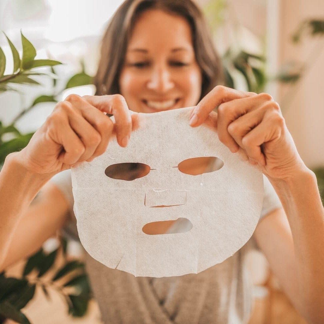 Woman smiling while preparing to apply an Orgaid Organic Sheet Mask