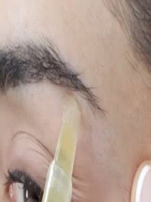 Parissa Brow Waxing Pen gel being applied precisely beneath the eyebrow with the angled applicator tip.