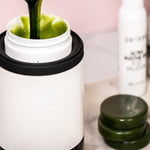 Dark green Parissa Brazilian and Underarm Hot Wax being lifted from a white wax warmer with a wooden applicator.