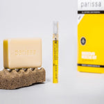 Parissa Ingrown Rescue Kit with pale exfoliating bar, slim yellow serum tube and yellow carton arranged on a white surface with a textured pad.