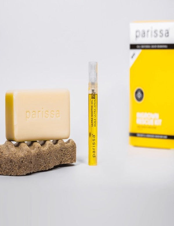 Parissa Ingrown Rescue Kit with pale exfoliating bar, slim yellow serum tube and yellow carton arranged on a white surface with a textured pad.