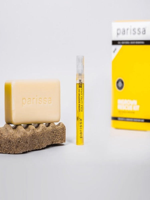 Parissa Ingrown Rescue Kit with pale exfoliating bar, slim yellow serum tube and yellow carton arranged on a white surface with a textured pad.