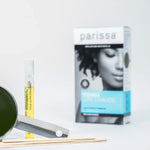 Small metal pan of dark green wax, wooden spatulas and a slim yellow-labelled tube arranged in front of a Parissa Face and Lip Hot Wax box.