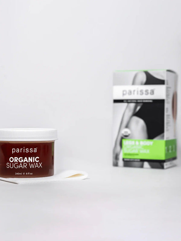 Parissa Organic Sugar Wax jar with a white lid beside a small white spatula, with its green-panel box in the background.