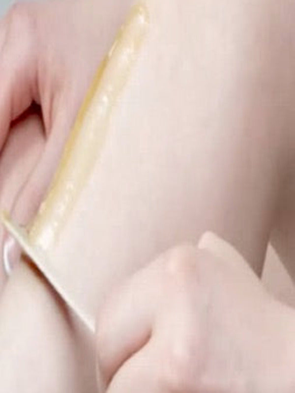 Close-up of a strip of Parissa Organic Sugar Wax being pulled smoothly from the skin on a person's leg.
