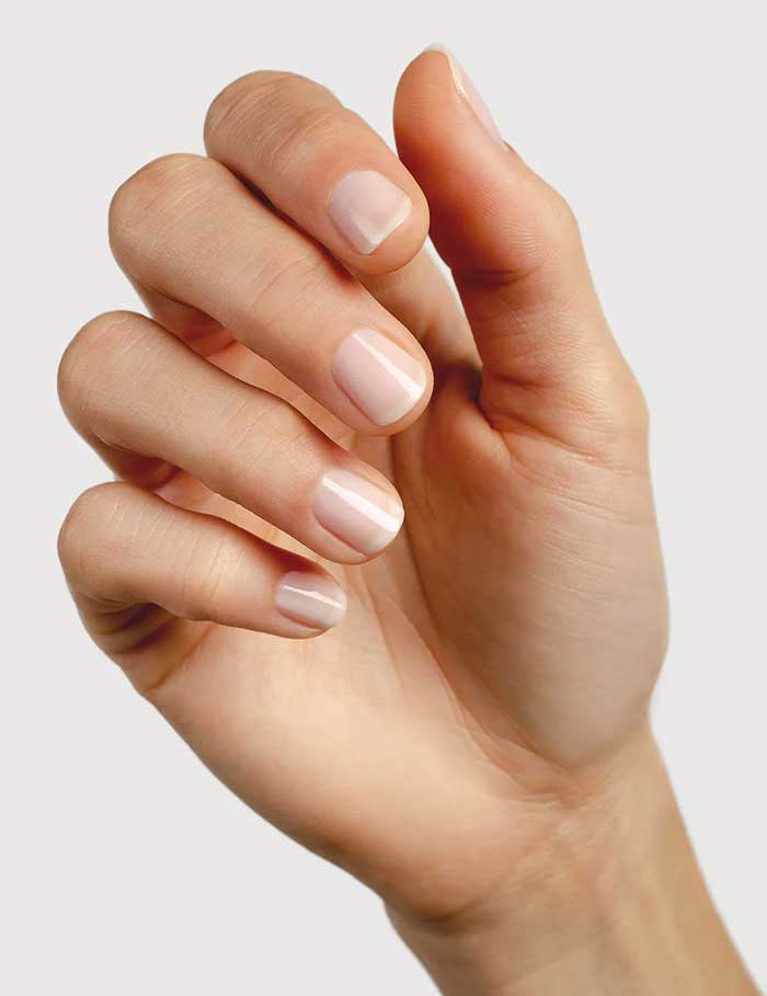 A close-up of a hand with natural, neatly manicured nails against a plain light background, featuring short nails with a glossy finish created using Sienna Byron Bay Nail Polish - Peace 10ml.