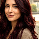 Woman modelling Radico Burgundy hair colour, looking back over one shoulder with long, loose waves in a deep wine-red shade.