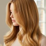Side view of a woman with long honey-gold hair falling in broad, smooth waves, with a small label beneath identifying the shade as Golden Blonde.