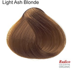 Rounded teardrop-shaped tuft of smooth, muted brown hair with lighter golden strands beneath the shade name Light Ash Blonde, with the Radico Colour Me Organic logo at the lower right.