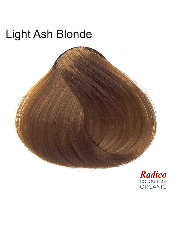 Rounded teardrop-shaped tuft of smooth, muted brown hair with lighter golden strands beneath the shade name Light Ash Blonde, with the Radico Colour Me Organic logo at the lower right.