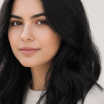 Woman modelling Radico Soft Black hair colour, with a centre part and glossy black hair falling in loose waves around her shoulders.