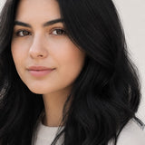 Woman modelling Radico Soft Black hair colour, with a centre part and glossy black hair falling in loose waves around her shoulders.